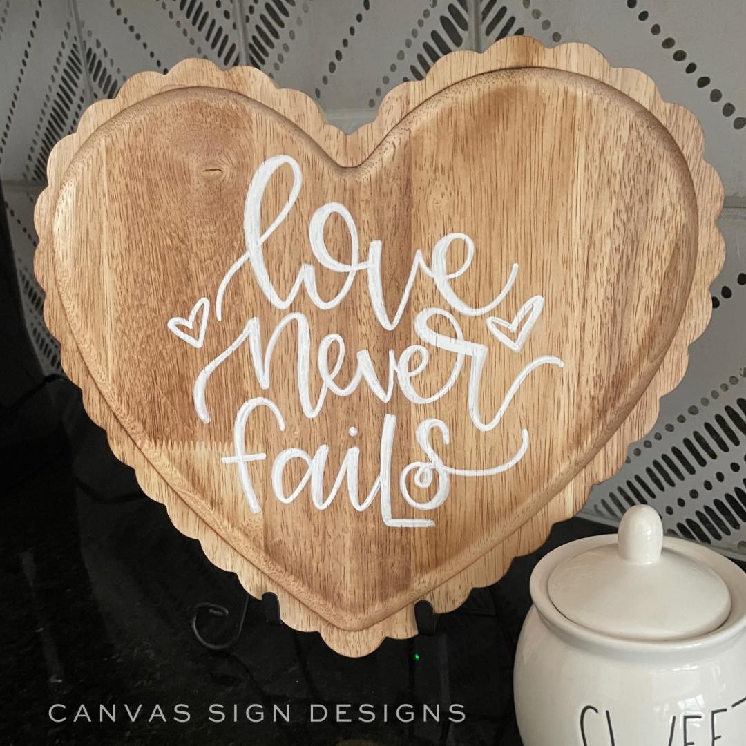 Love never fails hand lettered on a wooden heart