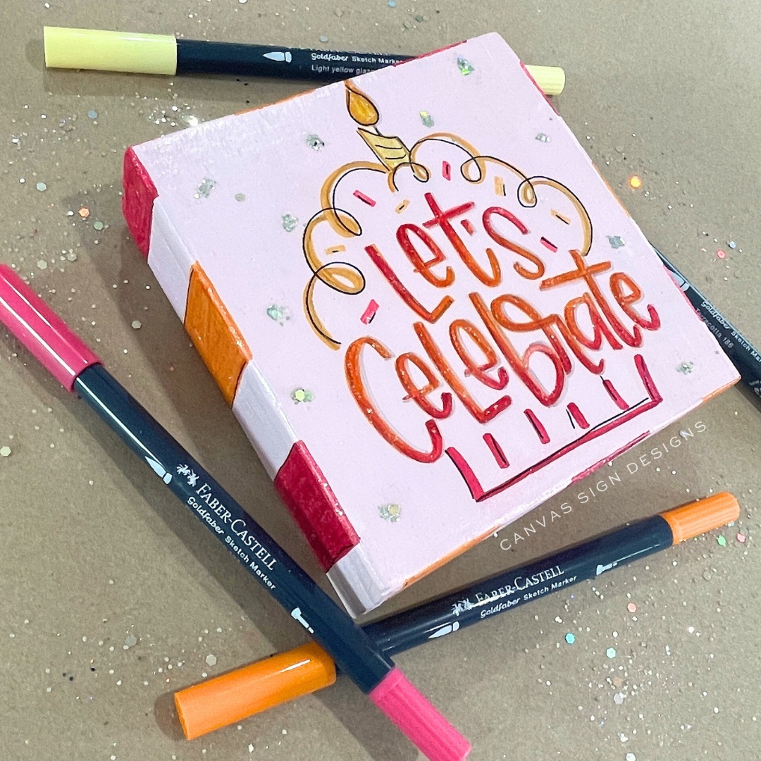 Red, pink, yellow, and orange ombre "Let's Celebrate" cupcake lettered on wood sign